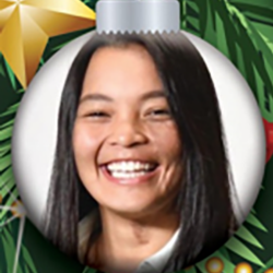 A smiling woman with straight dark hair is shown inside a Christmas ornament, with green pine branches and a gold star in the background.
