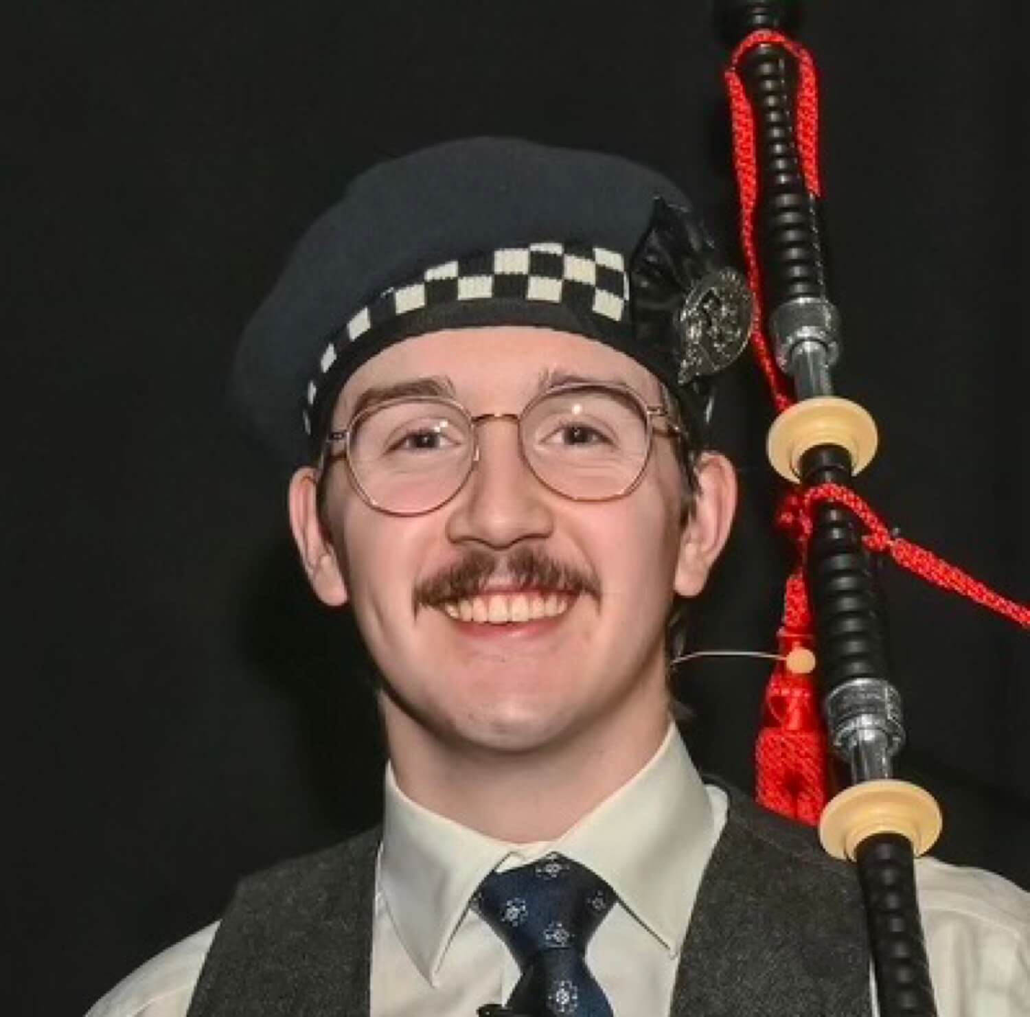 Liam Horne smiling and holding bagpipes
