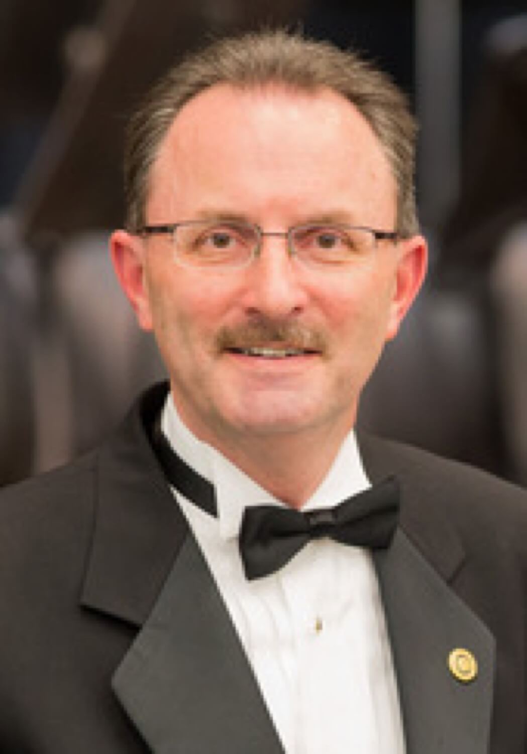 Mark Collins smiling in a black tuxedo